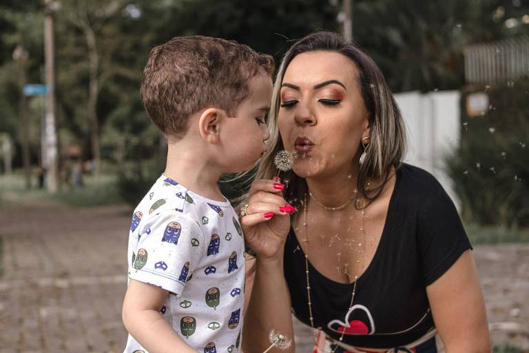 mãe e filho assoprando flor dente de leão no parque Bacacheri em Curitiba
