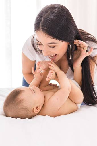 Mãe e filho bebê brincando na cama