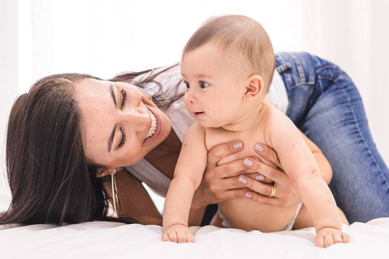 Mãe e filho bebê brincando na cama
