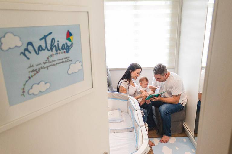 Pai, mãe e filho bebê lendo livro de histórias no quarto do bebê