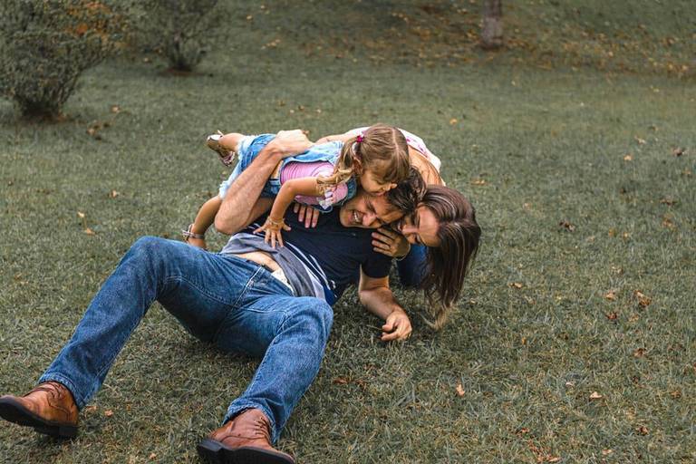 Mãe e pai e filha brincando ele abraçando no parque Tanguá em Curitiba 
