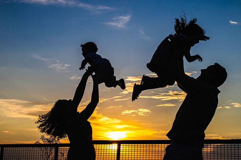 pais levantando filhos para o alto no pôr do sol no Parque Tanguá em Curitiba