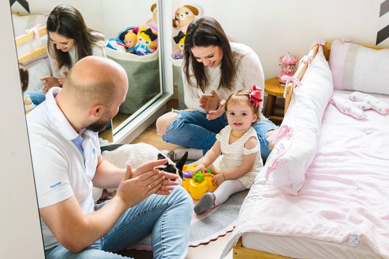 Pai, mãe e filha bebê brincando no quarto da filha