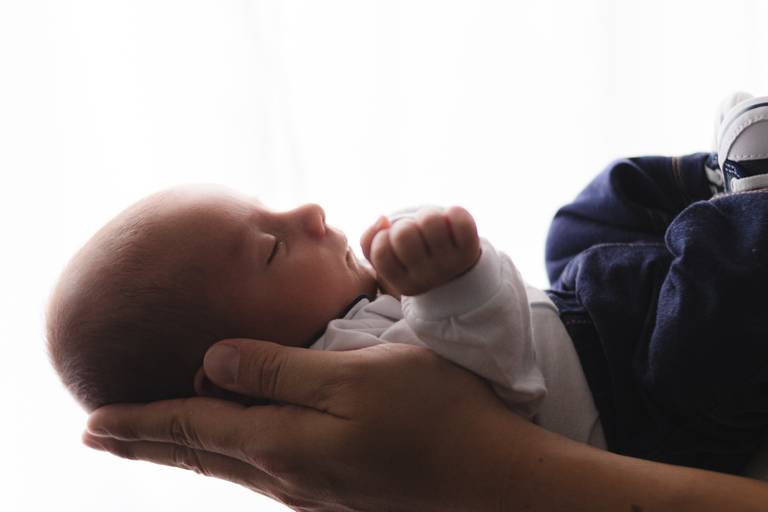 bebê recém nascido na mão do pai
