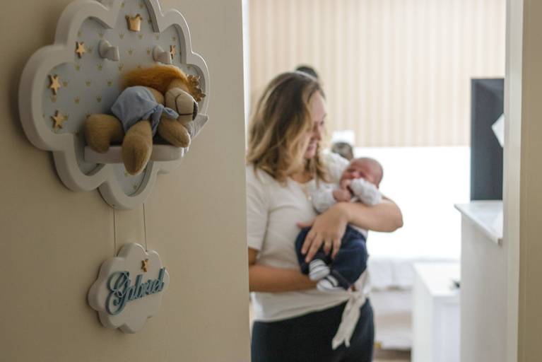 bebê recém nascido no colo da mãe com enfeite de porta aparecendo