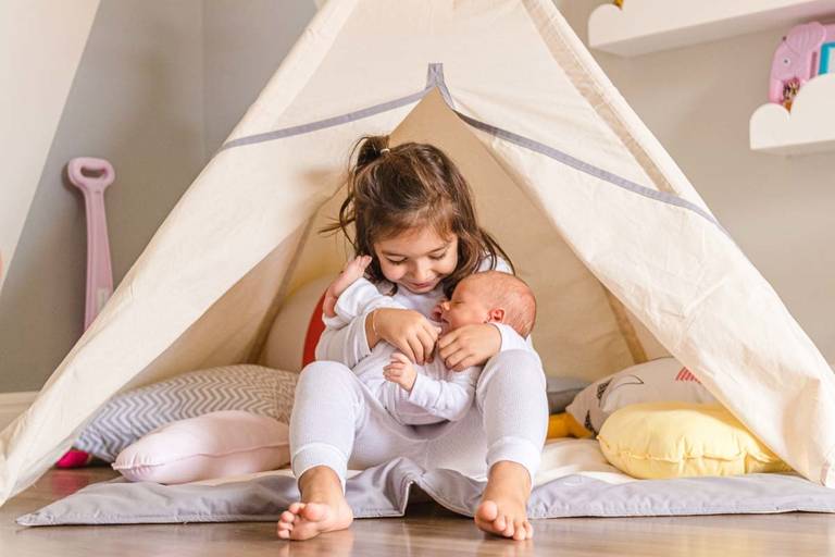 menina com irmã bebê no colo  no ensaio de newborn lifestyle