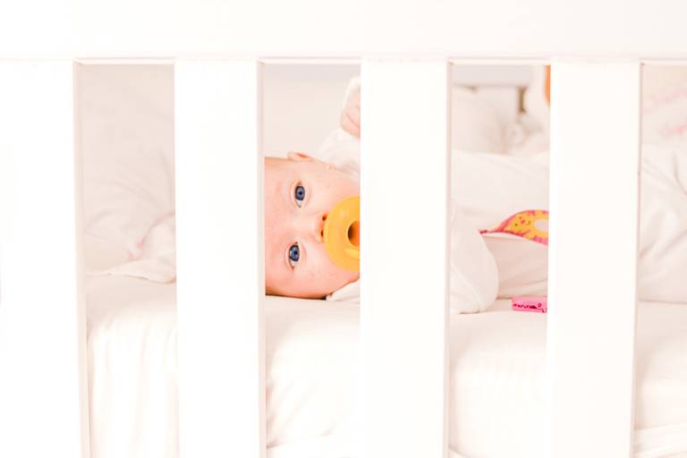 bebê chupando chupeta deitada no berço