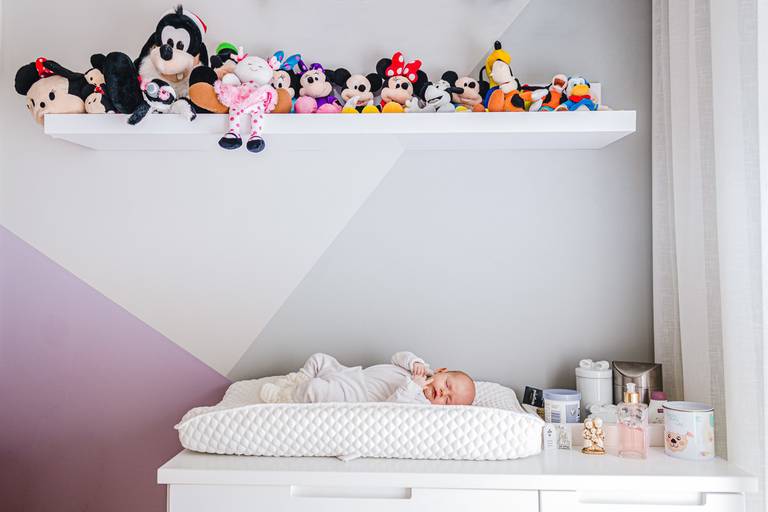 Bebê deitada no trocado com decoração do quarto