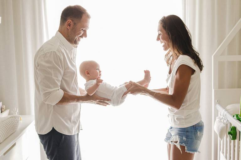 pais segurando bebê recém nascido nos braços 