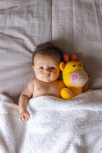 bebê deitada na cama com urso de pelúcia 