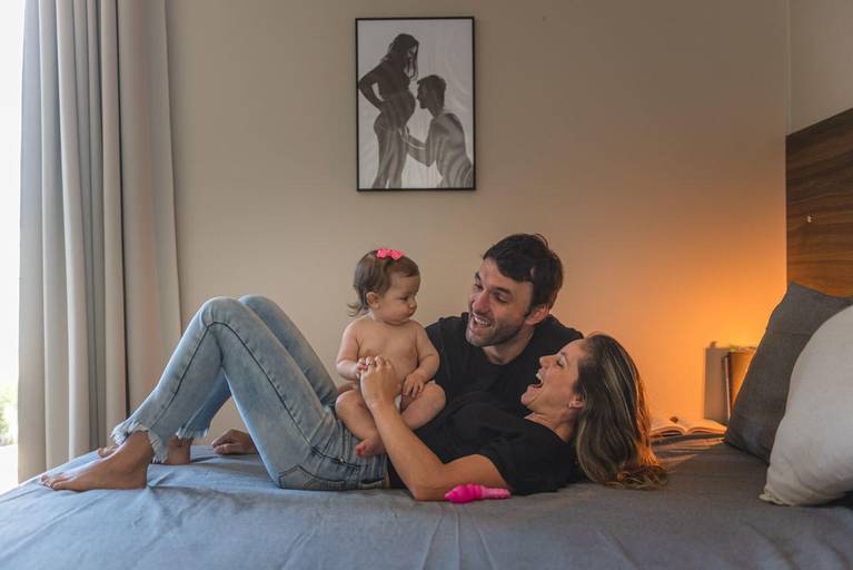 pais na cama brincando com bebê de 6 meses