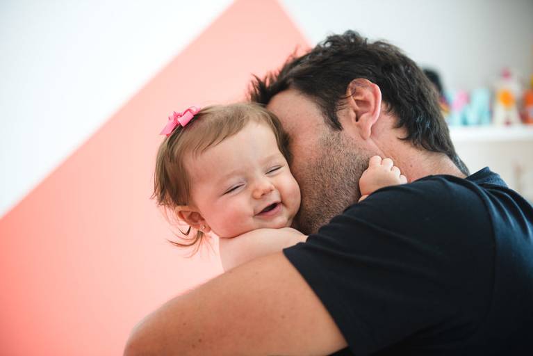 pai brincando com filha no colo