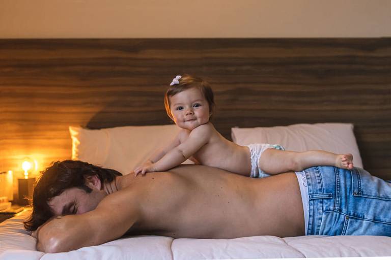 Bebê de 9 meses deitada nas costas do pai