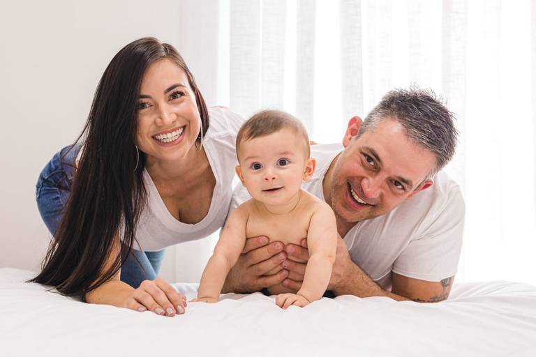 pais na cama brincando com bebê de 4 meses