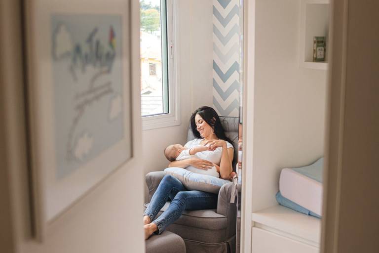 mãe amamentando sentada na cadeira do quarto do bebê