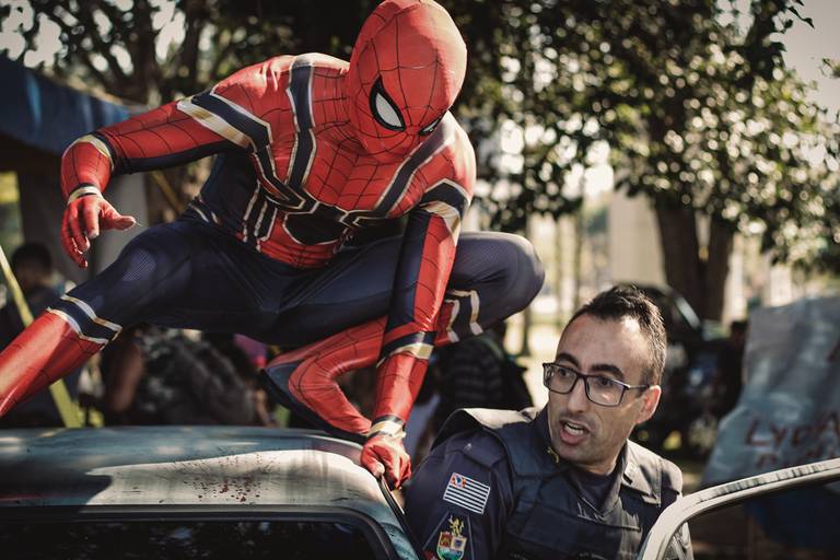 fotografia do homem aranha realizando uma cena de filme em que ele se prepara para uma chamada policial em cima de uma viatura