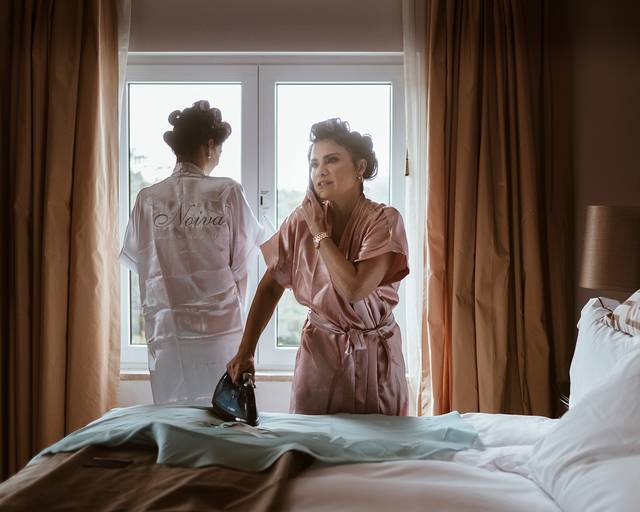 fotografia da mãe da noiva a passar a ferro o seu vestido