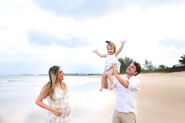 pai jogando filha para cima e se divertindo no ensaio de gestante. Filha participando do book de gestante