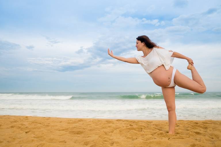 grávida Thaísa fazendo yoga na praia numa sessão fotográfica gestante lifestyle