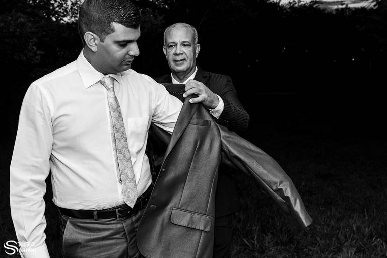 Pai colocando terno no noivo 
